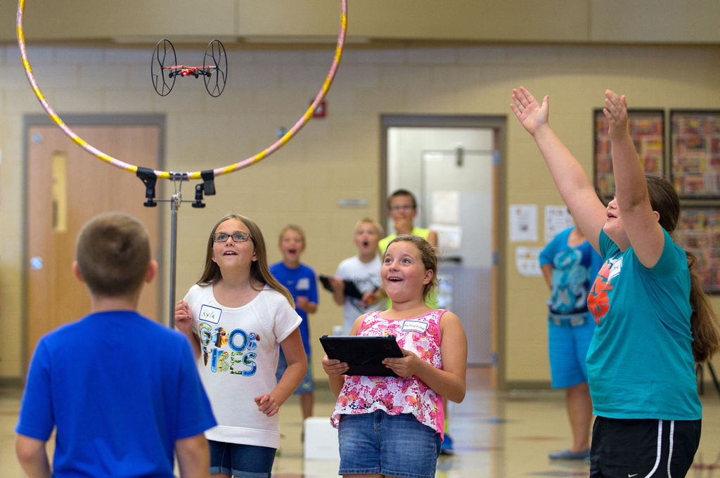 Fifth-graders fly a Parrot Rolling Spider through a hula hoop as part of an experiment. 